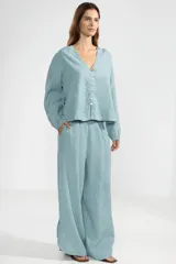 Pantalón celeste de lino italiano, de pierna ancha, con cintura elástica ajustable con cordón, bolsillos laterales y cortes redondeados en los laterales.