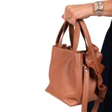 Cartera mini de cuero graneado color marrón, con doble asa de mano, correa larga desmontable y detalle de volado confeccionado a mano en cuero.