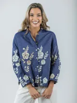 Camisa de jean azul con bordado de flores en tonos champagne y cobre, cuello mao y corte amplio.