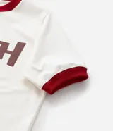 Remera blanca de algodón y elastano con cuello y mangas cortas con borde rojo. Estampa frontal del personaje Stitch de Disney.
