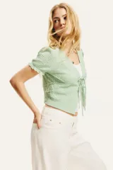 Top corto verde agua en punto arrugado con escote en V y doble cordón de ajuste abajo del busto que se enlaza adelante. Mangas cortas con elástico revestido y ribete sobrehilado.