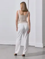 Pantalón de lino a rayas verticales color beige y blanco, con pretina ancha elastizada, lazo de ajuste y bolsillos inclinados.