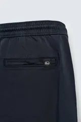 Pantalón jogger negro de corte slim fit, confeccionado en tejido de algodón con cintura elástica ajustable con cordón, bolsillos frontales y traseros de vivo, y bajo con puño elástico.