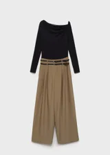 Mono largo de poliéster color caqui, con cuello asimétrico, manga larga, bolsillos laterales, cierre de cremallera lateral y cinturón con hebilla metálica.