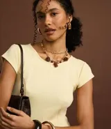 Vestido negro de punto Roma, corto, con escote redondo y mangas cortas. Presenta recortes en el talle que definen la silueta ajustada en el torso y falda acampanada.