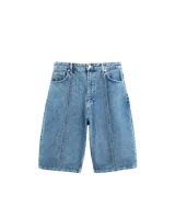Bermuda de jean azul de corte amplio, con costuras expuestas en delantero y trasero, y bolsillos traseros grandes.