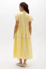 Vestido midi amarillo de lino, con volados en las mangas y detalle de volados y botones a lo largo del frente. Presenta un corte con talle marcado y falda escalonada.