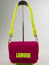 Cartera bandolera fucsia con patrón acolchado y ribete amarillo neón. Tiene asa corta trenzada color verde neón y logo "LAMODE" estampado en amarillo neón.