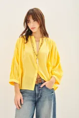 Camisa amarilla de algodón con corte amplio, cuello redondo y mangas 3/4 con puños elásticos.