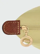 Mochila plegable Longchamp modelo Le Pliage Original, color beige claro, con solapa y asas de cuero marrón.