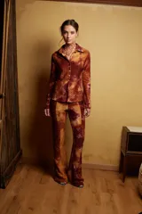 Pantalón de tiro medio con elástico en la cintura y corte acampanado. Diseño con estampado abstracto en tonos marrones, rojizos y amarillos, con textura tipo piel de reptil.