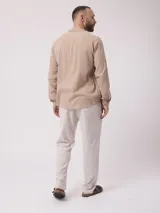 Pantalón largo de hombre, color beige con finas rayas verticales blancas, de corte recto y estilo pijamero.