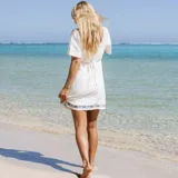 Vestido corto color blanco, con escote cuadrado, mangas cortas abullonadas y bordado de flores azules en el ruedo.