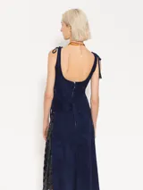 Pollera midi de cuero caprino color azul marino, con vuelo y tela complementaria con bordado de lentejuelas en los laterales. Presenta ojalillos de níquel en el frente y cierre metálico en la espalda.