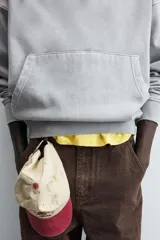 Sudadera gris con capucha ajustable, corte boxy fit, manga larga, bolsillo tipo canguro y estampado en la espalda.