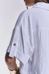 Camisa blanca de mangas cortas con dobladillo, cuello clásico, cierre frontal con botones y dos bolsillos frontales con solapa.