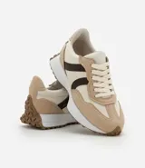 Championes de estilo jogging para mujer, confeccionados en poliuretano color tostado con recortes contrastantes en color crema. Presentan cierre de cordones blancos y suela de PVC que se extiende hasta el talón con base dentada.