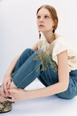 Pantalón de jean tiro alto con corte paper bag, lazo a tono en la cintura y bordado con lentejuelas y piedras en el lateral.