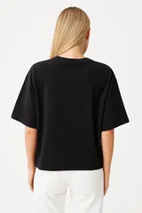 Remera negra de algodón, manga 3/4, cuello a la base y corte holgado.