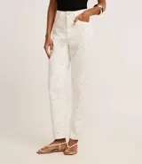 Pantalón mom comfort de cintura alta confeccionado en sarga color crudo, con trabillas en la cintura, cierre tradicional, bolsillos y brillo aplicado con lunares metalizados y pedrería de strass.