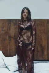 Vestido midi semitransparente de encaje floral color borgoña, con cuello barco, mangas largas y espalda con escote en V. Presenta costuras marcadas y terminaciones onduladas.