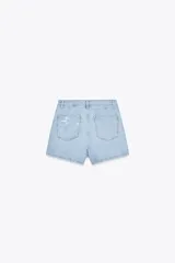 Falda pantalón de tiro alto de denim celeste con efecto lavado y roturas frontales. Tiene cinco bolsillos y cierre frontal con cremallera oculta y botones.