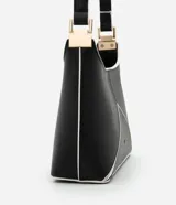 Cartera baguette mediana de cuero sintético color negro, con recortes geométricos en blanco en el frente y asa corta con detalle metálico.
