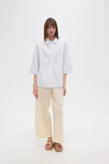 Camisa celeste a rayas verticales, de corte holgado y manga 3/4.