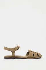 Sandalias cangrejeras planas de serraje color beige, con puntera redondeada y cierre de hebilla lateral ajustable.