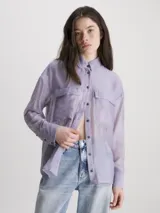 Camisa Calvin Klein de lyocell color lila, de corte holgado, manga larga, cuello en punta, cierre de botones, bolsillos con solapa en el pecho y logo bordado en el bolsillo del pecho.