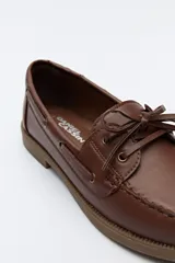 Zapato náutico color beige, de símil cuero, con cordones y suela marrón antideslizante.