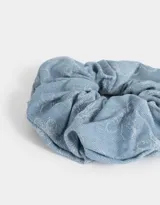 Gomita de pelo tipo scrunchie de tela denim celeste con diseño de flores grabadas con láser.