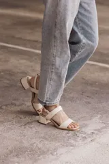 Sandalia de cuero color beige claro (off white) con taco ancho y tiras finas ajustables con hebilla metálica dorada en el tobillo.