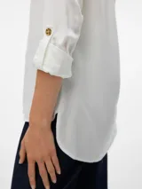 Camisa blanca de mangas largas con vuelta, cuello clásico, cierre frontal con botones y dos bolsillos con solapa en el pecho.