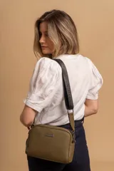 Bandolera pequeña de textura símil cuero color caramelo/marrón, con dos compartimentos principales con cierre. Correa ancha ajustable de tela negra con inscripción en relieve.