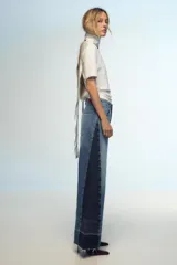 Pantalón de jean de tiro medio con cinco bolsillos, corte wide leg y detalle de tejido con lavado lateral combinado.