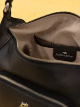Bandolera negra de cuero vacuno con correa fina ajustable. Tiene cierre superior y forro interior de tejido jacquard. Incluye bolsillos frontales y laterales con cierre dorado y logo de la marca en dorado.
