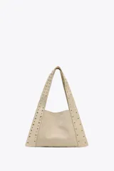 Bolso de hombro color beige, confeccionado en serraje, con tachas metálicas doradas en el cuerpo y las asas. Cuenta con un bolsillo interior y cierre mediante botón imantado.