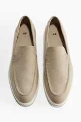Mocasines color beige de gamuza con costura tradicional y suela blanca de goma.
