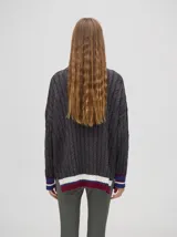 Sweater tejido de algodón color rosa claro, con cuello polo con cierre de cremallera metálica y mangas largas con puños a rayas de colores.