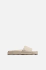 Sandalias tipo pala color beige, con suela de goma con volumen y tira ancha en el empeine con relieve.