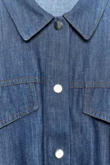Cazadora de denim azul con mezcla de algodón y lino. Tiene cuello solapa, manga corta con vuelta y trabilla con botón, bolsillos de plastrón en el delantero, bajo elástico y cierre frontal con botones.
