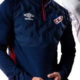 Buzo de entrenamiento azul marino con cierre parcial rojo, escudo del Club Nacional de Football y logo de Umbro en el pecho.