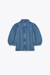Blusa de denim con cuello solapa y manga abullonada por debajo del codo. Cierre frontal con botones.