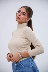 Polera de punto acanalado color beige, con cuello alto y mangas largas.