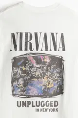 Remera blanca de corte amplio con cuello redondo y mangas cortas. Estampado frontal con el logo de Nirvana y la leyenda "Unplugged in New York".