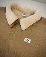 Buzo beige de pana con cuello alto forrado en corderito blanco, cierre parcial con cremallera, puños y cintura elastizados.