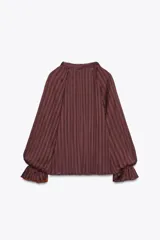 Blusa color marrón con rayas verticales, cuello subido con lazo, escote pico, mangas largas abullonadas con elástico en los puños y cierre frontal con botones forrados.