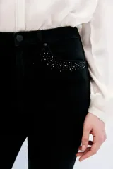 Jean slim negro de tiro medio-alto, calce al cuerpo y pierna semi-recta. Detalle de hotfix en bolsillos.