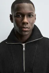 Jersey de punto perlado negro, de corte relaxed fit, con cuello perkins y cierre frontal de cremallera.